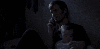 a man holding a baby while talking on a cell phone