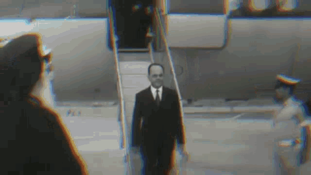 a man in a suit and tie is walking down a set of stairs .