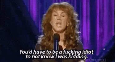 a woman is giving a speech in front of a microphone and saying you 'd have to be a fucking idiot