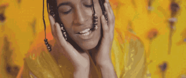 a man with dreadlocks is smiling in front of a yellow background with flowers