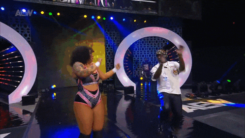 a man and a woman are dancing on a stage with a sign that says aew in the background