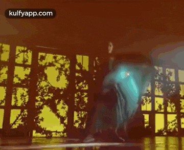 a woman in a blue dress is dancing in a room with a lot of windows .