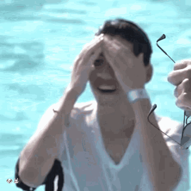 a man in a white shirt covering his face with his hands