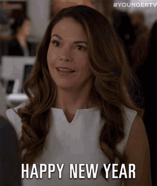 a woman says " happy new year " while wearing a white shirt