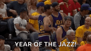 a group of people are sitting in a stadium watching a basketball game and one of the players is hugging another player .