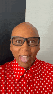 a bald man wearing glasses and a red and white polka dot shirt is sticking his tongue out .