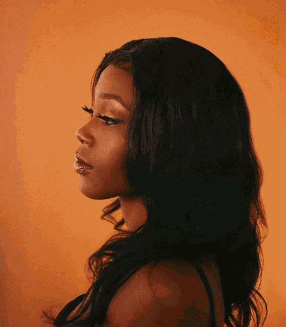 a woman 's face is shown in a close up against an orange background