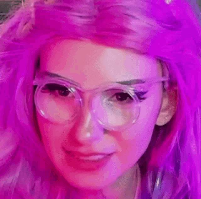 a close up of a woman wearing glasses and a purple wig .