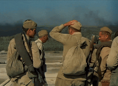 a group of soldiers standing in a field with smoke coming out of the trees
