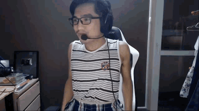 a man wearing a striped shirt and headphones is standing in front of a window