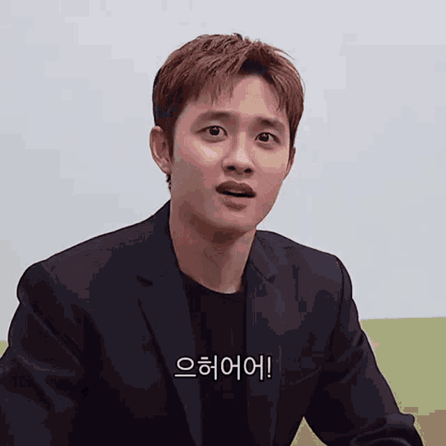 a man in a suit is making a funny face while sitting on a couch .