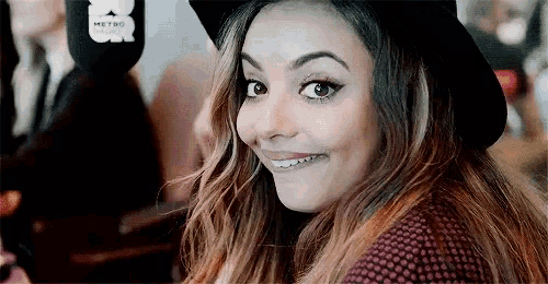 a woman wearing a hat and a sweater is smiling .