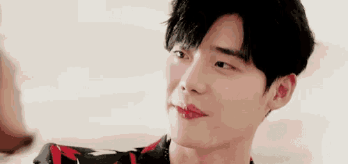 a close up of a young man 's face with red lips and a floral shirt .