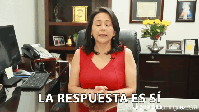 a woman in a red top is sitting at a desk with the words la respuesta es si written below her