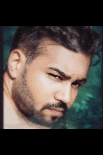 a man with a beard is looking at the camera with a green background