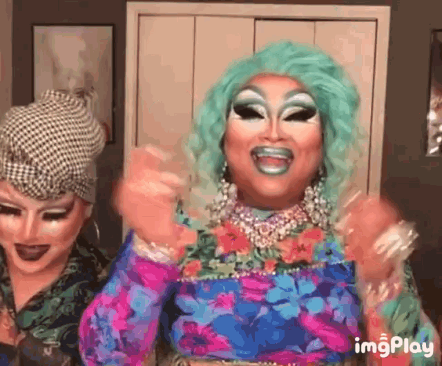 two drag queens are posing for a picture and one has a blue wig