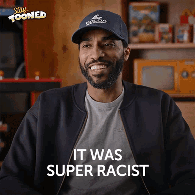 a man wearing a blue kolda hat is smiling and saying it was super racist