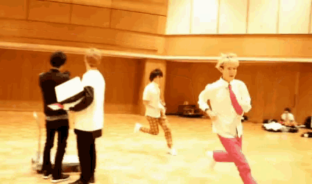 a woman in pink pants is running in a room with other people