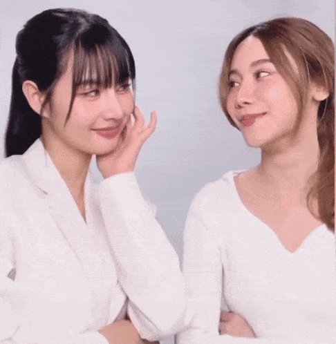 two women are laughing together and one is covering her mouth with her hand