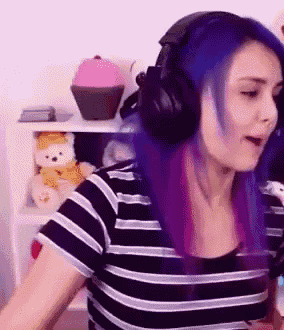 a woman with blue and purple hair wearing headphones and a striped shirt