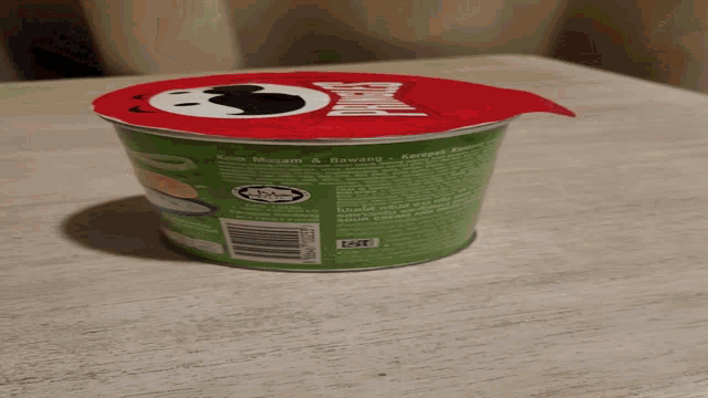 a can of pringles sits on a table with a red lid