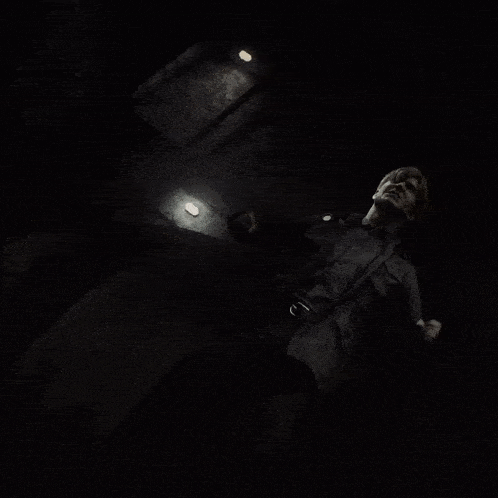 a man in a dark room with a light on