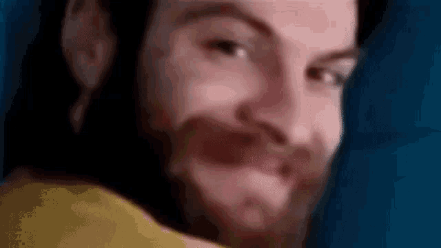 a man with a beard is making a funny face while looking at the camera .