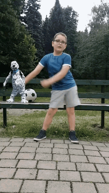a young boy playing with a soccer ball in front of a dalmatian puppet