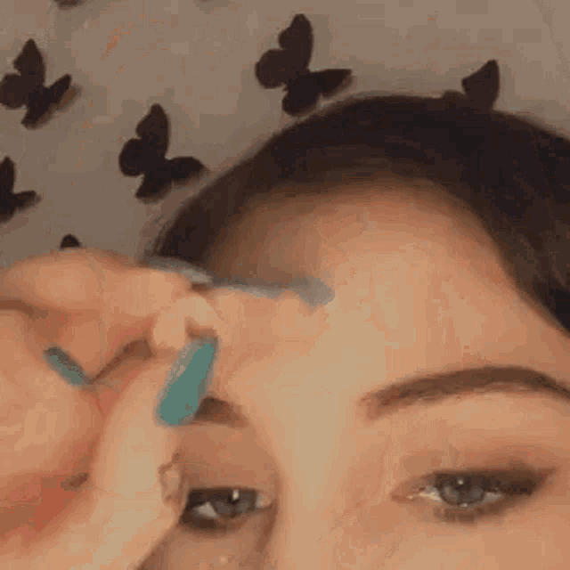 a woman is applying makeup to her face with a brush .