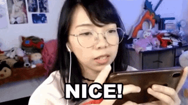 a woman wearing glasses and earbuds is holding a cell phone and says nice .