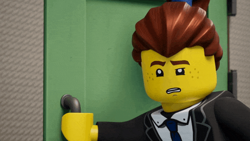 a lego man in a suit and tie is standing in front of a door