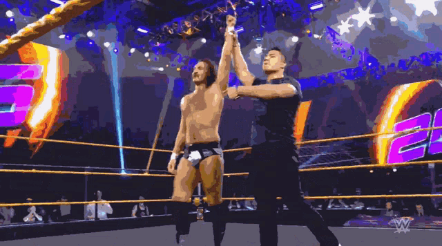 a wrestler is being congratulated by a referee