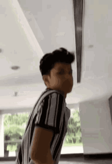 a boy in a striped shirt is standing in a room