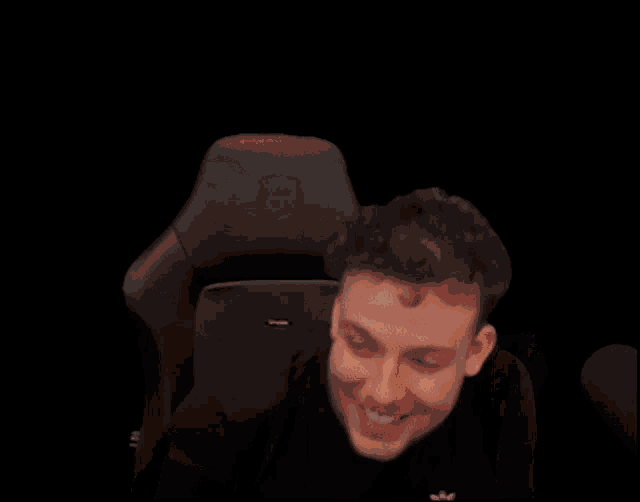 the man is sitting in a chair with his fist in the air .