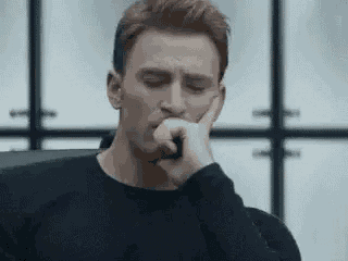 a man is sitting in a chair with his hand on his chin and his eyes closed .