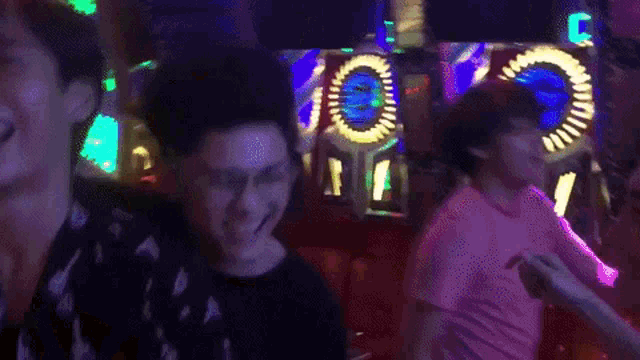 a group of people are dancing in a dark room with a clock in the background