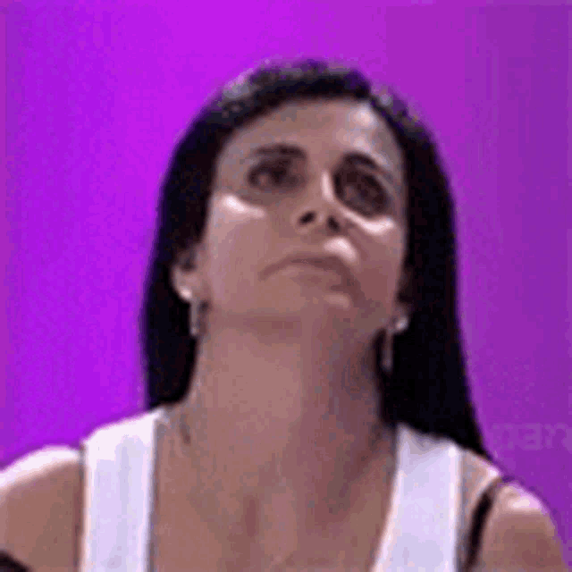 a woman with long black hair and earrings is looking up at the camera .