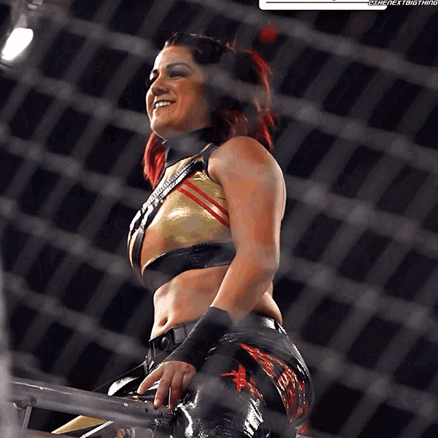 a female wrestler is smiling in front of a fence that says " the next thing " on it