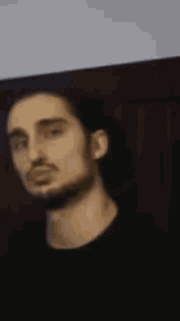 a man with long hair and a beard is making a funny face in a blurry photo .