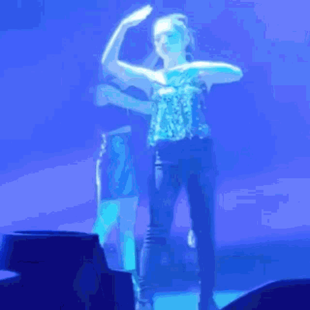 a woman is dancing on a stage in front of a blue background .