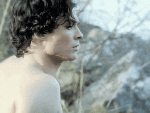 a man without a shirt is looking at something in the distance