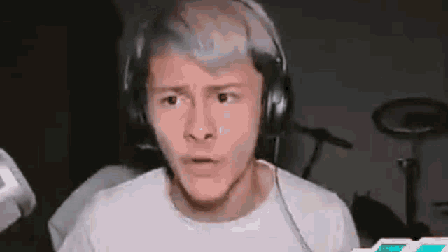 a man wearing headphones is making a funny face while sitting in front of a microphone .