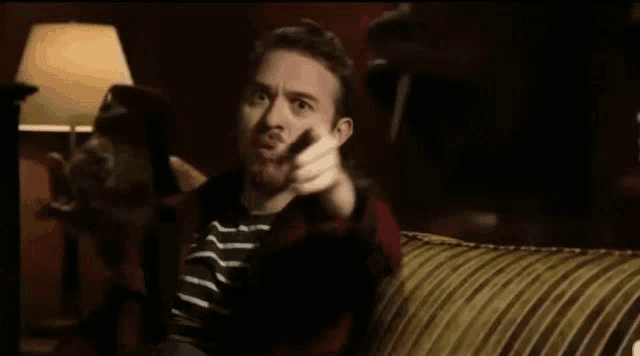 a man with a beard is making a funny face while sitting in a chair .