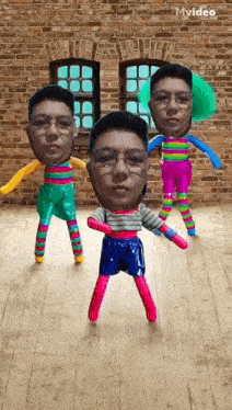 three dolls with faces on them are dancing in a room with a brick wall