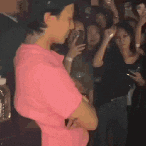 a man in a pink shirt stands in front of a crowd of people