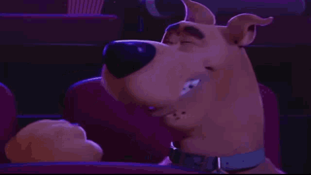 scooby doo is sitting in a theater seat with his eyes closed and smiling .