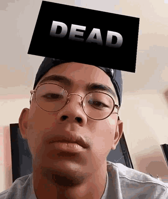 a man wearing glasses and a hat with a dead sign on his head