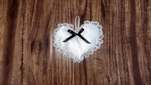 a heart shaped pillow with a black bow on a wooden table