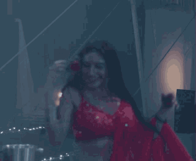 a woman in a red top is dancing in a dark room