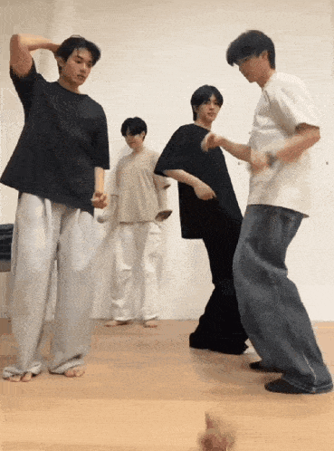 a group of young men are dancing on a wood floor